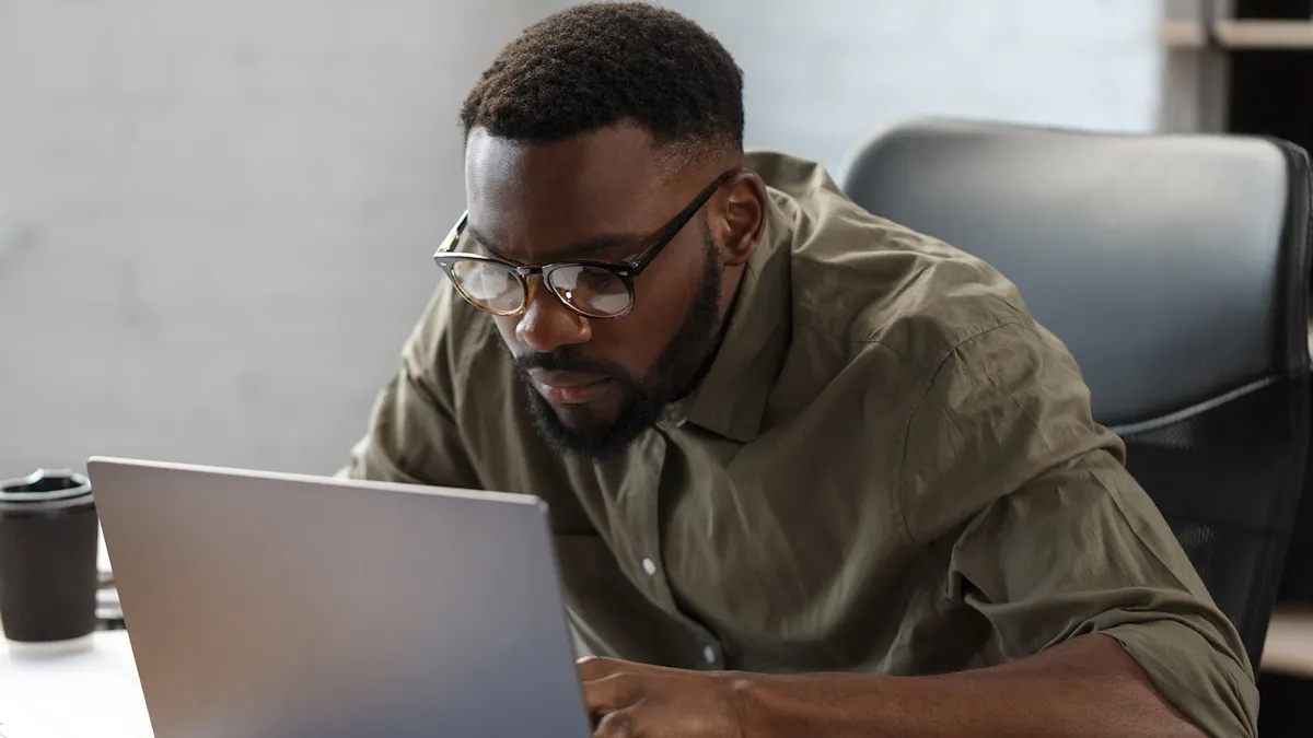Black man wearing glasses leans in to computer