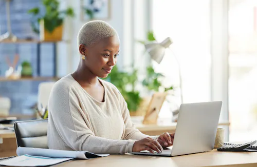 Woman smiling and typing at laptop