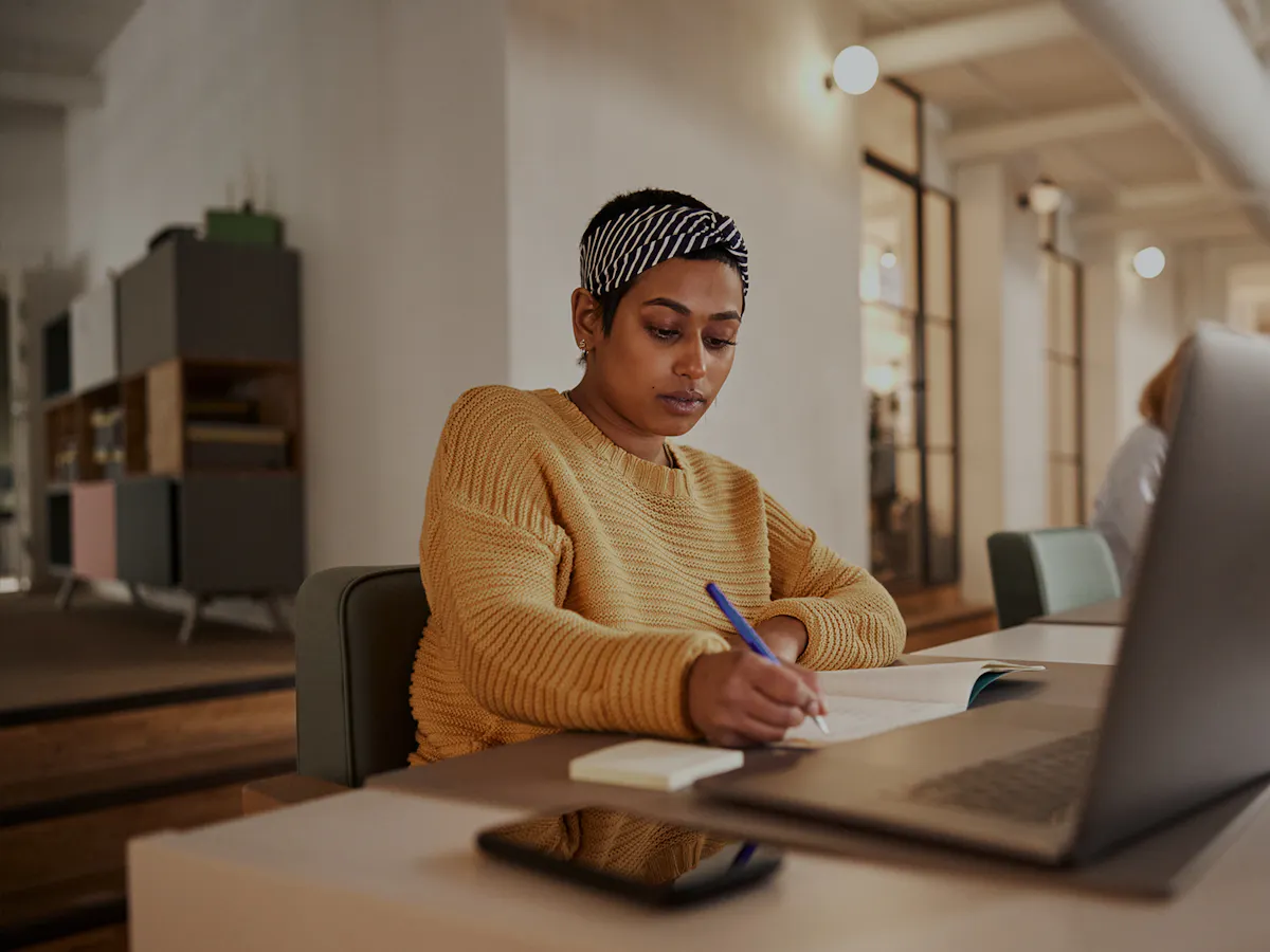 Woman writing in notebook in office space