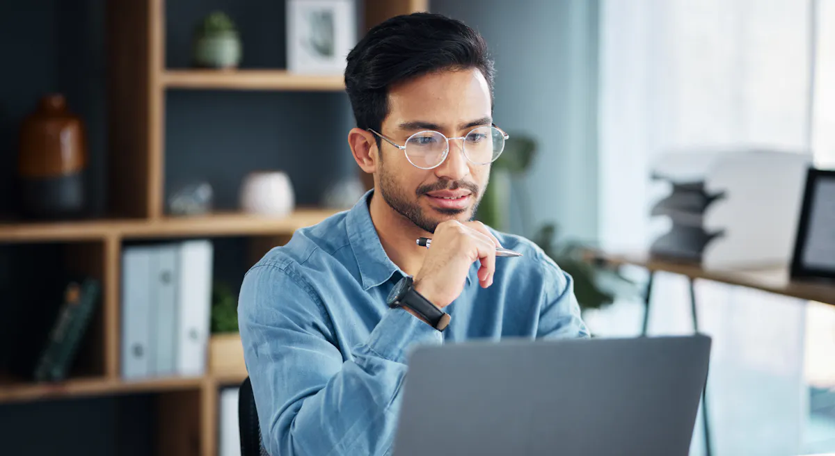 Man in glasses staring intently at laptop