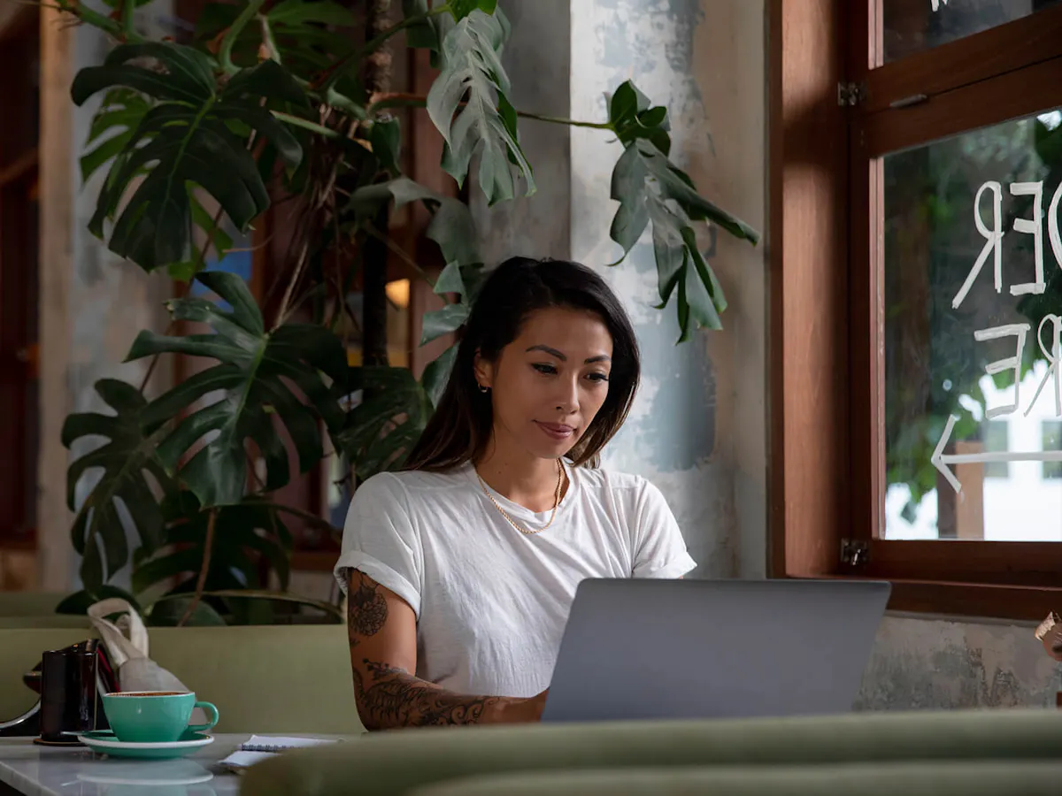 Woman with tattoo working from coffee shop