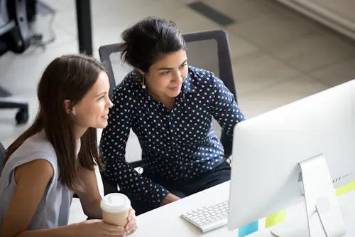 Two women looking at desktop together