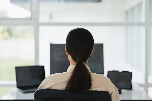 Woman working on dual monitors coding