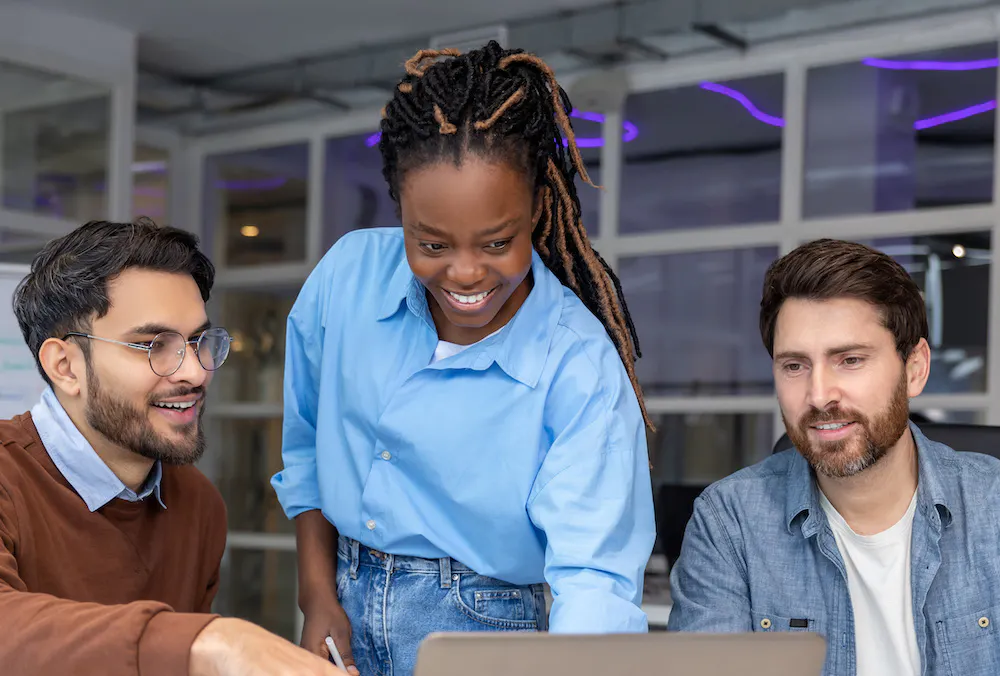 Three web developers in a conference room looking at laptop for card