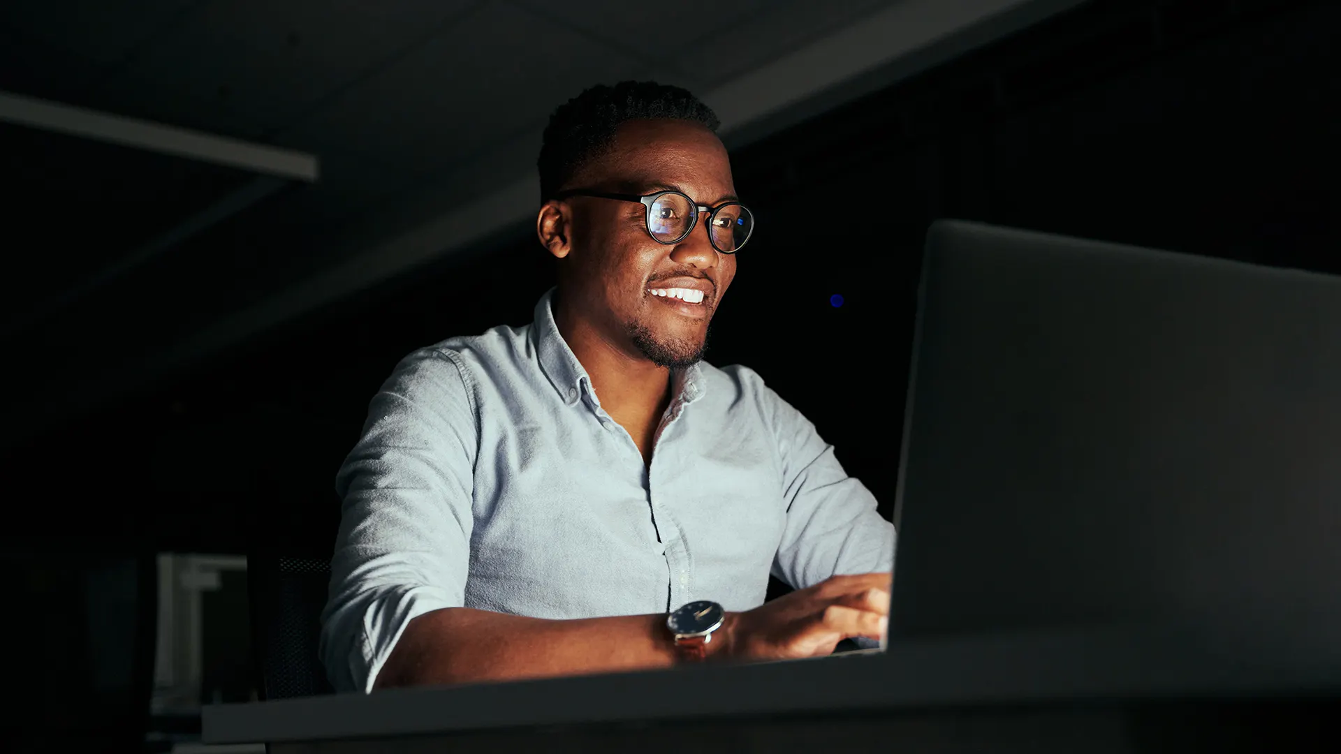 Man in glasses smiling at screen