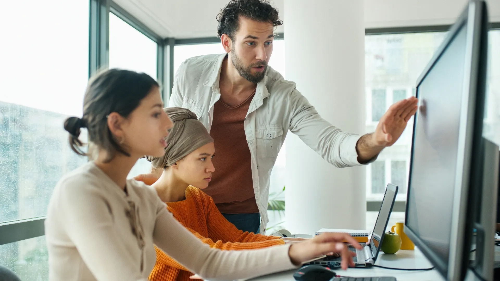 Two women and a man work on a AI data problem
