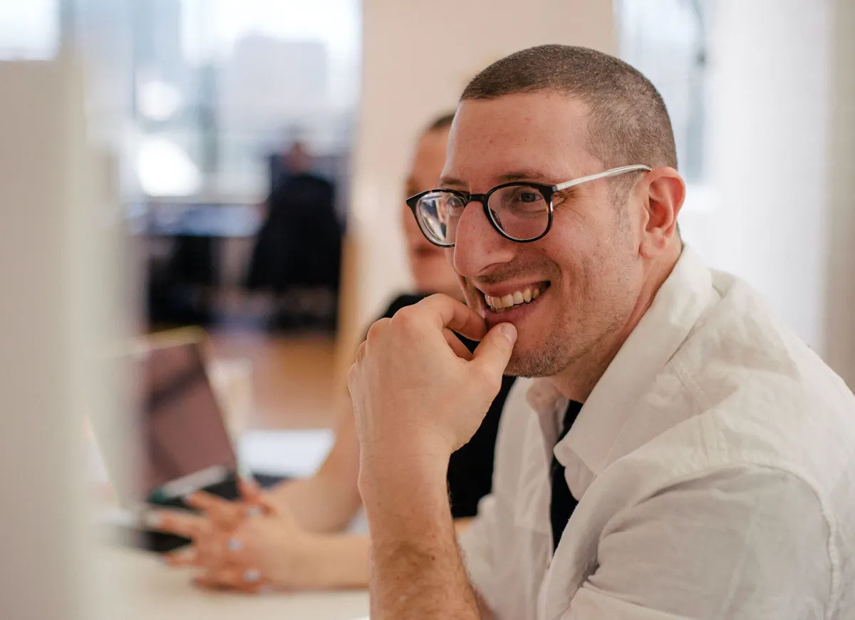 Man smiling glasses at computer