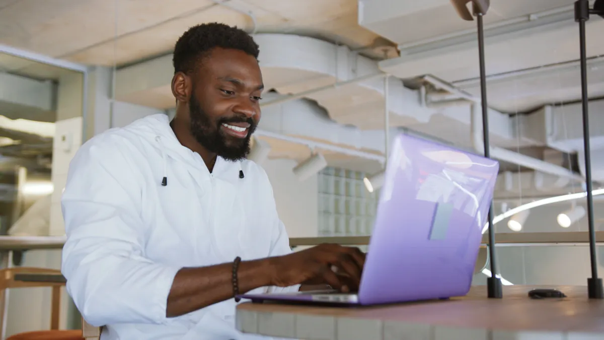 Black man with purple laptop smiles while working