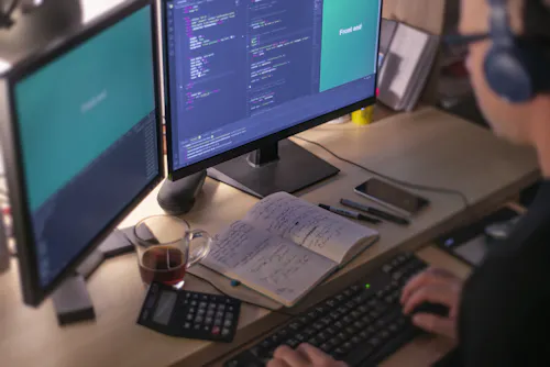 A coder works on a desktop computer.