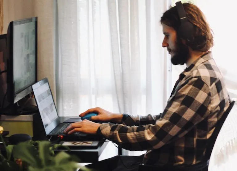 Mam working with laptop and monitor