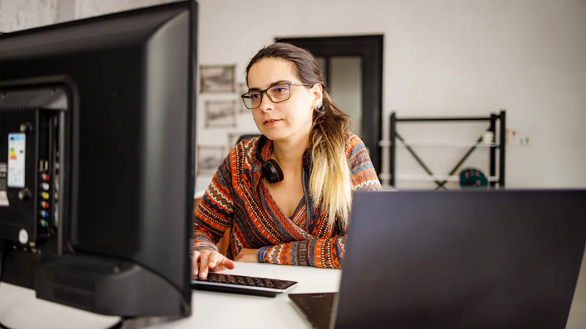 Woman in multicolor sweater looking at dual monitors