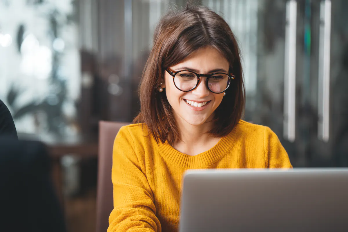 Woman wearing glasses smiling at computer