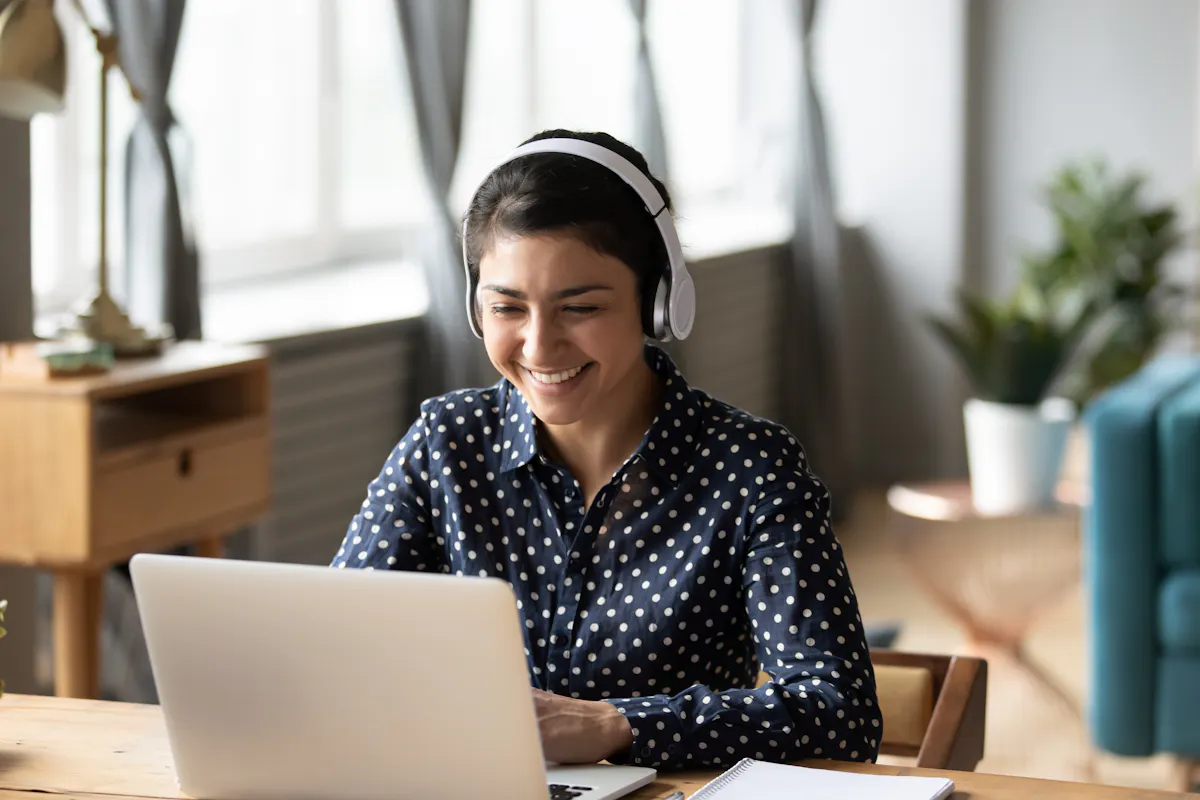 Woman with headphones smiles in online class